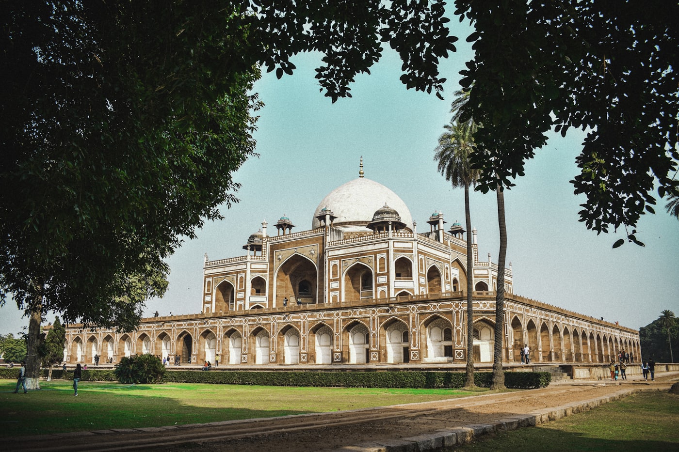 A Mughal-era monument in Delhi framed by large trees and lawns